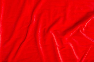 Renkli kırmızı tekstil kumaşı kıvrımlar ve dalgalar halinde kıvrılmış, parlak ışık ve desen parıldıyor.