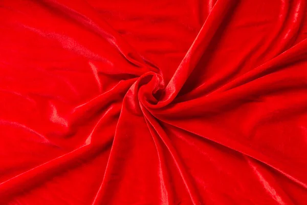 Renkli kırmızı tekstil kumaşı kıvrımlar ve dalgalar halinde kıvrılmış, parlak ışık ve desen parıldıyor.