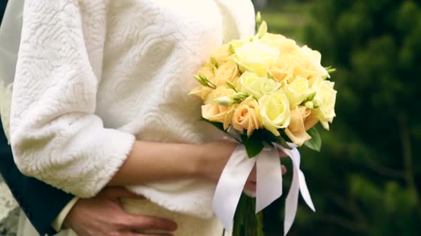 El ramo de boda de las flores en las manos de la novia sobre el fondo verde — Vídeos de Stock