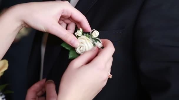 Невеста регулирует цветок на куртке жениха — стоковое видео