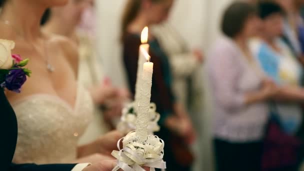 Ceremonia de boda en la iglesia ortodoxa. Novia y novio sosteniendo las velas. De cerca.. — Vídeo de stock