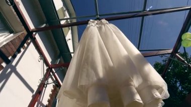 Güzel düğün elbisesi güzel dağ manzarası bir arka plan üzerinde asılı. Kahverengi ahşap kirişler balkon. Dağlar, orman, gökyüzü bir arka plan bir balkonda asılı elbise.