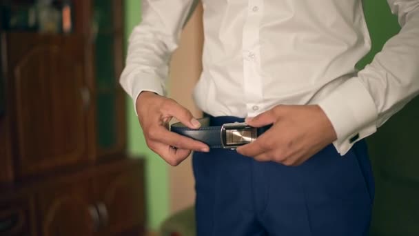 ベルトに入れての実業家。男は、茶色のベルトに置きます。バックルに焦点を当てます。新郎は結婚式のスーツ、ベルトに手を繋いでいます。