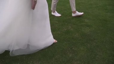 Gelin ve damat el ele, bacakları yakın.