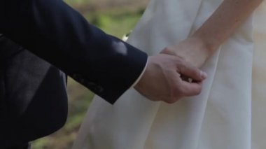 Yavaşça arka plan beyaz bir gelinlik üzerinde bir parmağına alyans ile bir yeni evli çiftin elleri bağlı