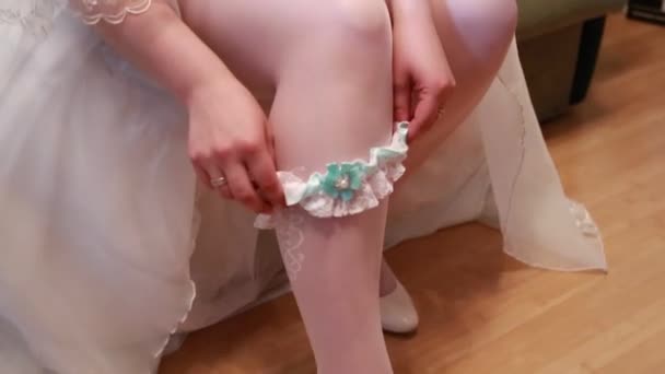 Sposa veste giarrettiera sulla gamba. Immagine di belle gambe scalze femminili in abito da sposa. Sposa veste calze a piedi. Sposa mettendo una giarrettiera di nozze sulla gamba — Video Stock