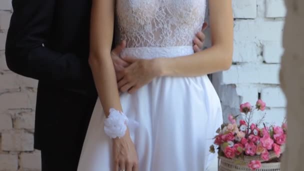 Manos suavemente conectadas de una pareja de recién casados con anillos de boda en un dedo sobre un fondo de un vestido de novia blanco — Vídeos de Stock