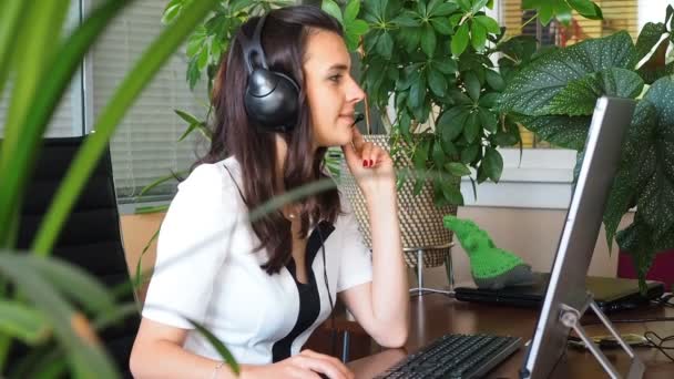 Frau spricht im Büro per Headset mit Klientin, die von Pflanzen umgeben ist — Stockvideo