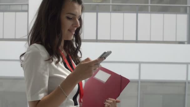 Elegante schöne Frau schaut auf Smartphone in Bürogebäude — Stockvideo