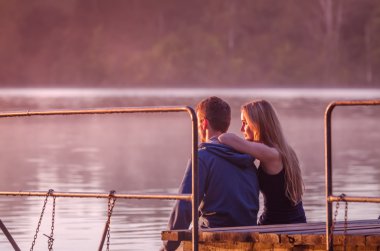 Muhteşem günbatımı zevk iskelede oturup Romantik Çift