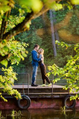 Adam suya yakın iskelede gün batımında kız arkadaşı sarılma