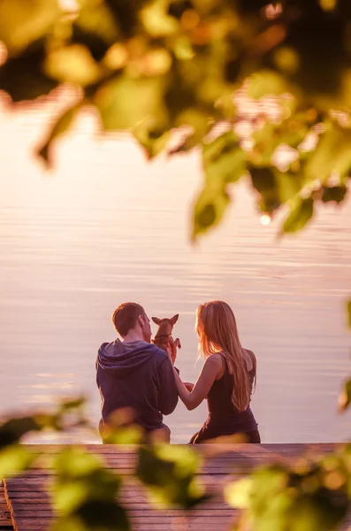 Pareja romántica sentada en el muelle disfrutando del impresionante atardecer — Foto de Stock