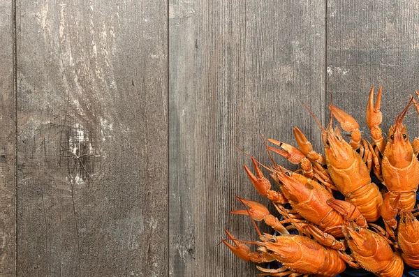 Plate of red crayfishes on old wooden table in left-bottom corner — Stock Photo, Image