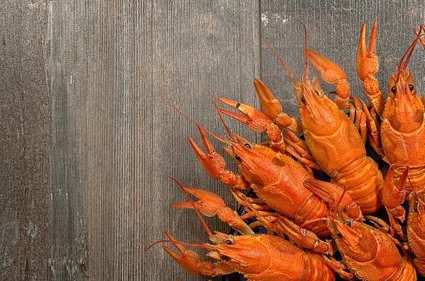 Plate of red crayfishes on old wooden table in left-bottom corner — Stock Photo, Image