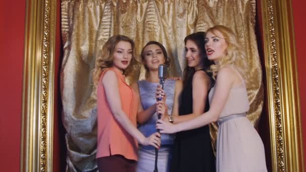 vier schöne stylische Mädchen singen Karaoke im Club