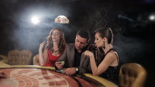der reiche Mann umgeben von zwei Prostituierten, um im Casino zu spielen und zu gewinnen