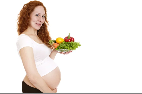 Těhotná žena držící zeleninu a usmívá se — Stock fotografie