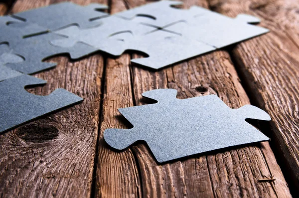 Incomplete puzzles lying on wooden rustic boards. — Stock Photo, Image