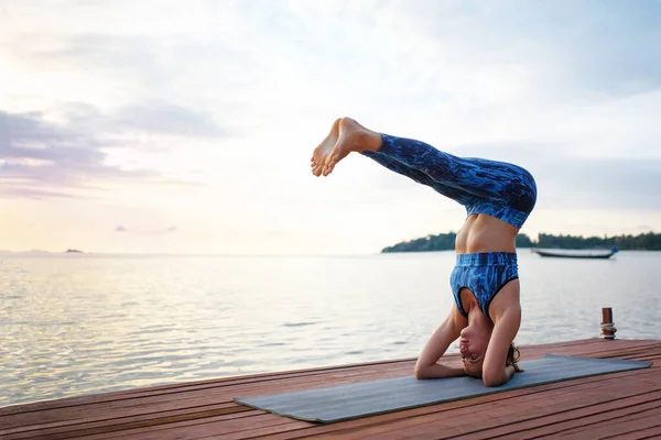 Young woman practicing yoga on the sunset beach