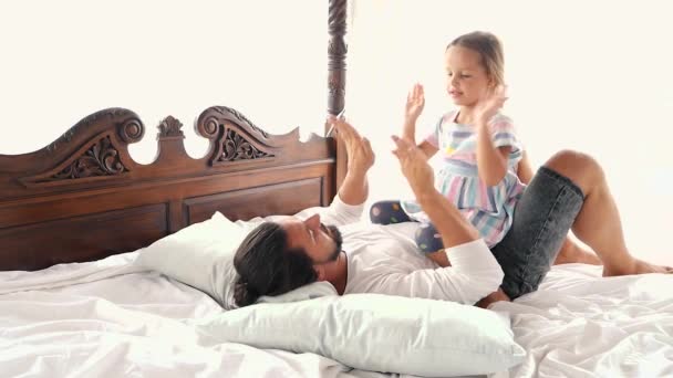 Feliz familia idilio hija pequeña saltar en los brazos del padre y caen en una cama — Vídeo de stock