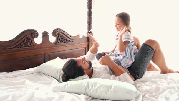 Família feliz Idyll criança pequena filha pular em braços do pai e eles caem em uma cama — Vídeo de Stock