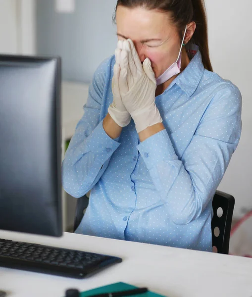 Нездоровая молодая женщина с ноутбуком в маске и кашле, работает дома или на работе, закрывается — стоковое фото