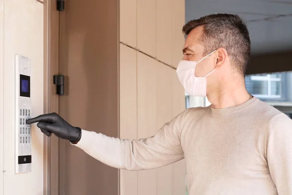 医療用マスクの男性はドアコードをダイヤルします。 ストック写真