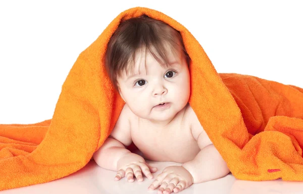 Baby liggend onder oranje handdoek — Stockfoto