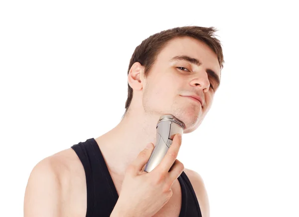 Ung mann som barberer av seg skjegget med en elektrisk barberkniv . – stockfoto