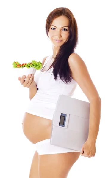 Mujer embarazada sosteniendo escamas y comiendo ensalada . — Foto de Stock