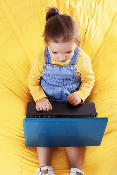 Kind zit op een zitzak met laptop — Stockfoto