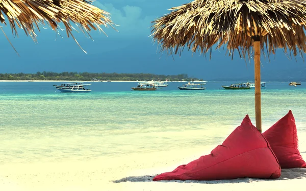 Paraguas y bolsa de frijoles en la orilla del mar . — Foto de Stock