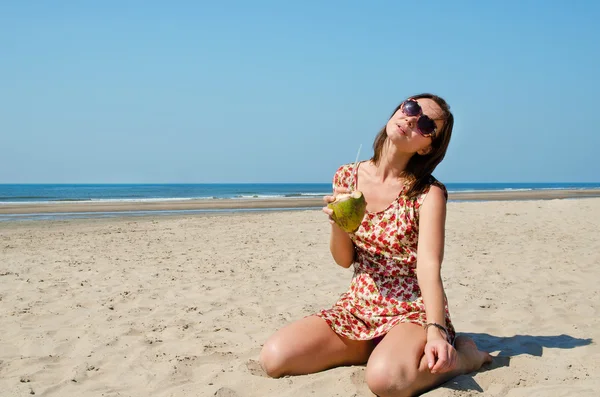 Ung kvinna dricka kokosmjölk på stranden. — Stockfoto