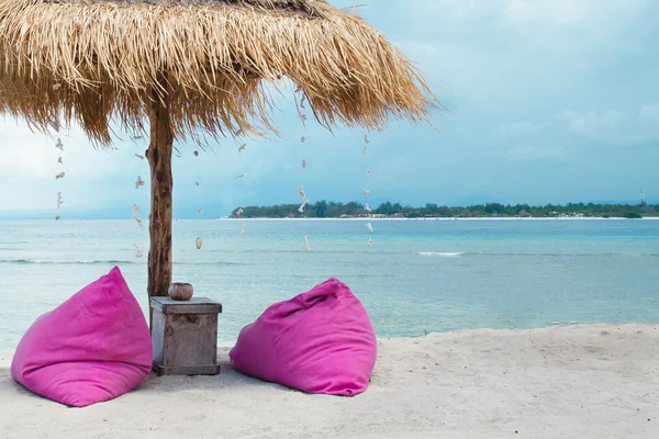 Sunbed and umbrella on a tropical beach - Stock image — Stock Photo, Image