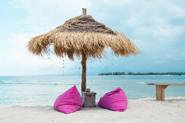 Sunbed and umbrella on a tropical beach - Stock image — Stock Photo, Image