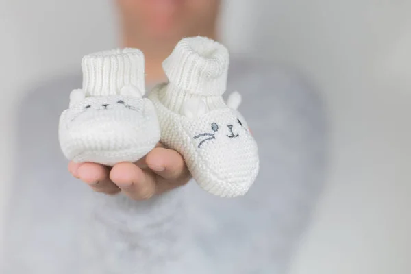 Male is holding pair of white baby wool shoes — Stock Photo, Image