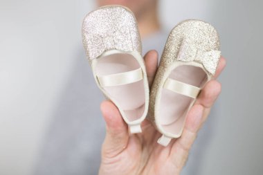 Güzel bir çift altın çocuk ayakkabısı. Erkeklerin elindeki kızlar için.