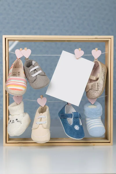 Set di scarpe bambino in una cornice di legno con sfondo grigio più biglietto di auguri — Foto Stock