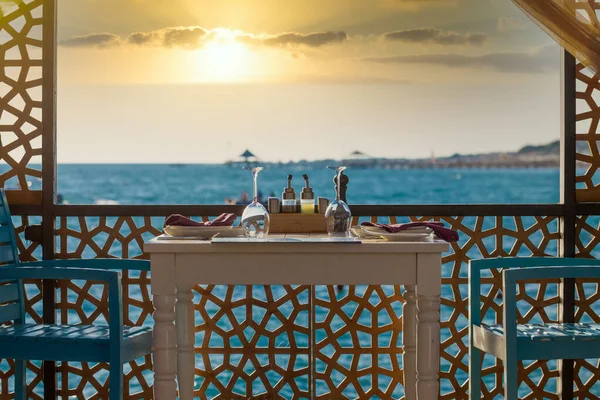 식탁과 의자 두 개, 포도주 잔, 해 가질 때의 터키 바다 모습이 있는 식당 — 스톡 사진