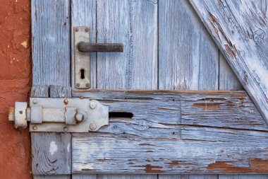 Kapalı ahşaptan yapılmış eski bir kapı ve kırmızı evin ön cephesinde barlar var. Hava izleriyle çok tüketilmiş. Yatay