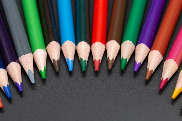 Colored pencils in close up for school and arts semicircular arranged with dark background and copy space for free text. Horizontal