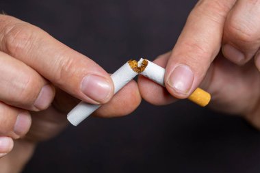 Bir insan sigarayı iki eliyle tutar ve onu kırar, sembolik olarak sigarayı bırakmak ve sağlığa dikkat etmek için. Yatay
