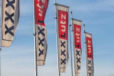Dreieich, Germany - February 20, 2021. Flags on the grounds of the furniture house xxxlutz or mannmobilia in front of blue sky. High quality photo