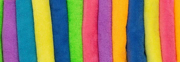 Towels and cleaning cloths in various colors as background to the topics shower, household and hygiene with the colors pink, yellow and blue. Horizontal wide