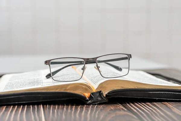 Glasses lie on an open bible on a white background.