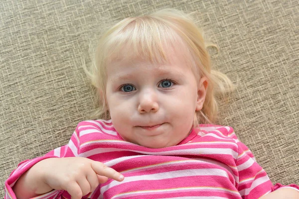 A child with an unusual face lies on the couch, close-up.