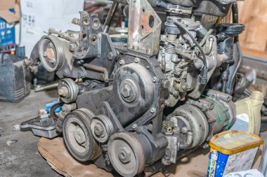 Eski, parçalanmış, kirli ve paslı bir motor atölyede yerde yatıyor..