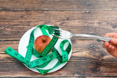 Çatallı bir çocuk yeşil bir santimetreyi tabakta bir elmanın üzerinde tutar..