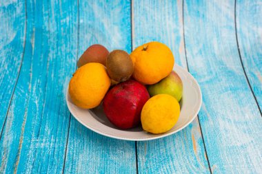 Mavi arka planda bir tabakta çeşitli meyveler var..