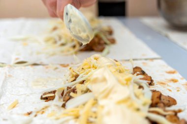 Kız kızarmadan önce shawarmaya sondan bir önceki bileşeni ekliyor..
